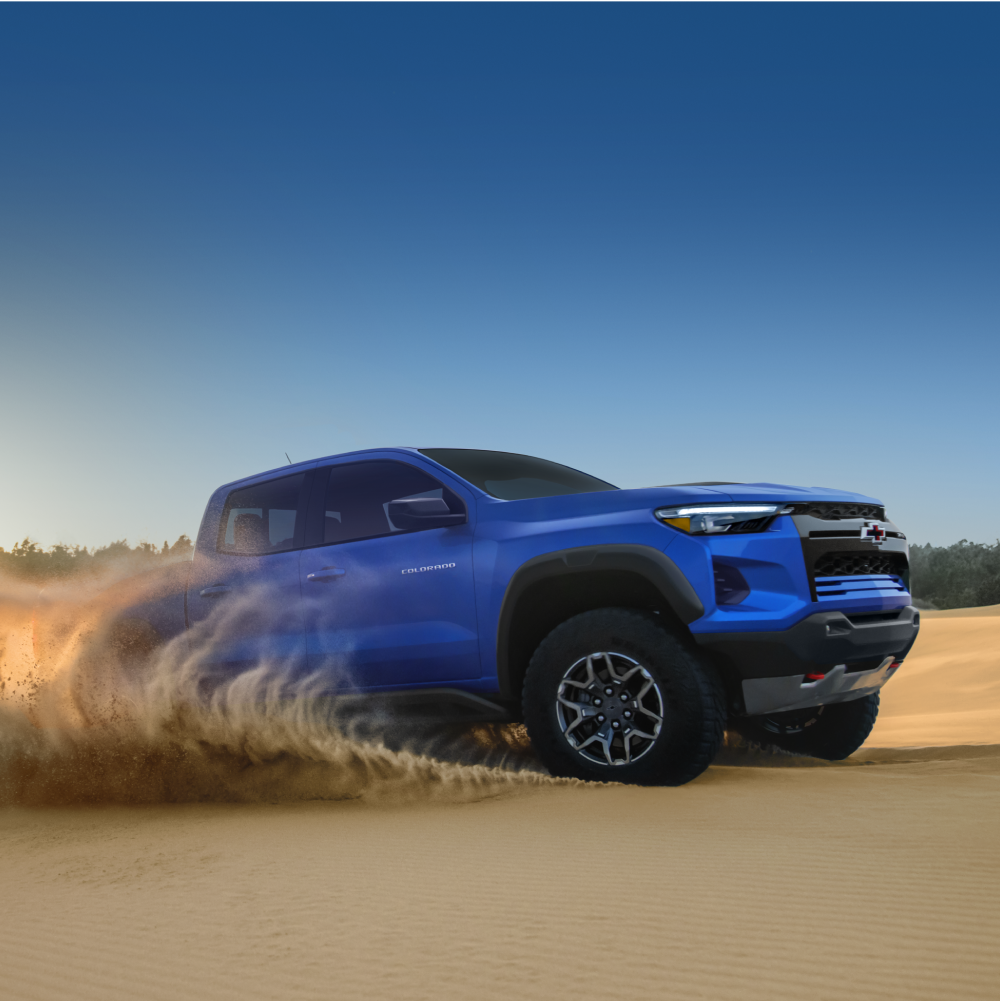 Front-Side View of a Blue 2026 Chevrolet Colorado Pickup Truck Driving in the Desert.