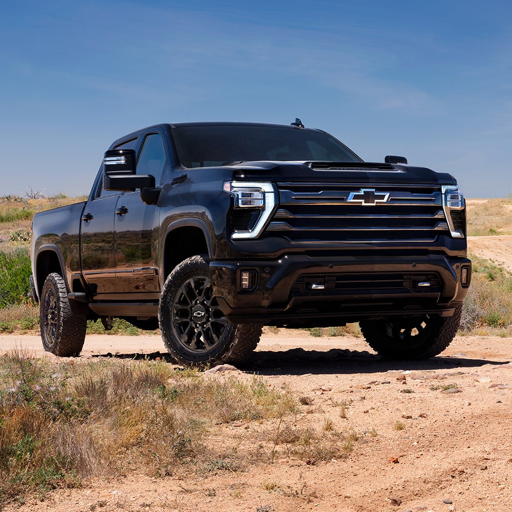 Vue latérale avant du Chevrolet Silverado HD 2026 stationné seul dans le désert.