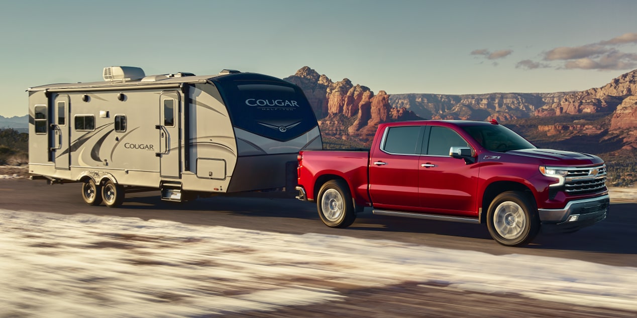 Le Chevrolet Silverado LD 2026 qui tire une grande remorque sur la route.