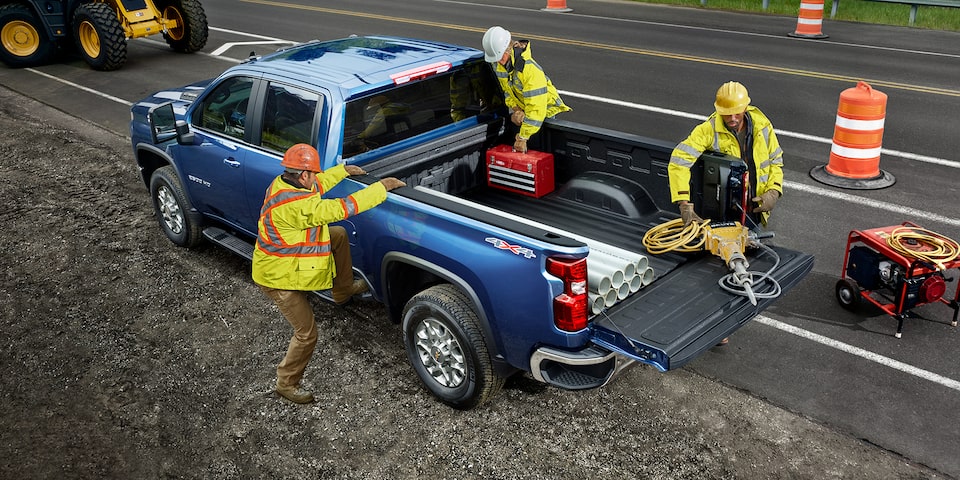 Deux hommes utilisant la benne du camion Chevrolet Silverado HD 2021 pour des travaux commerciaux.