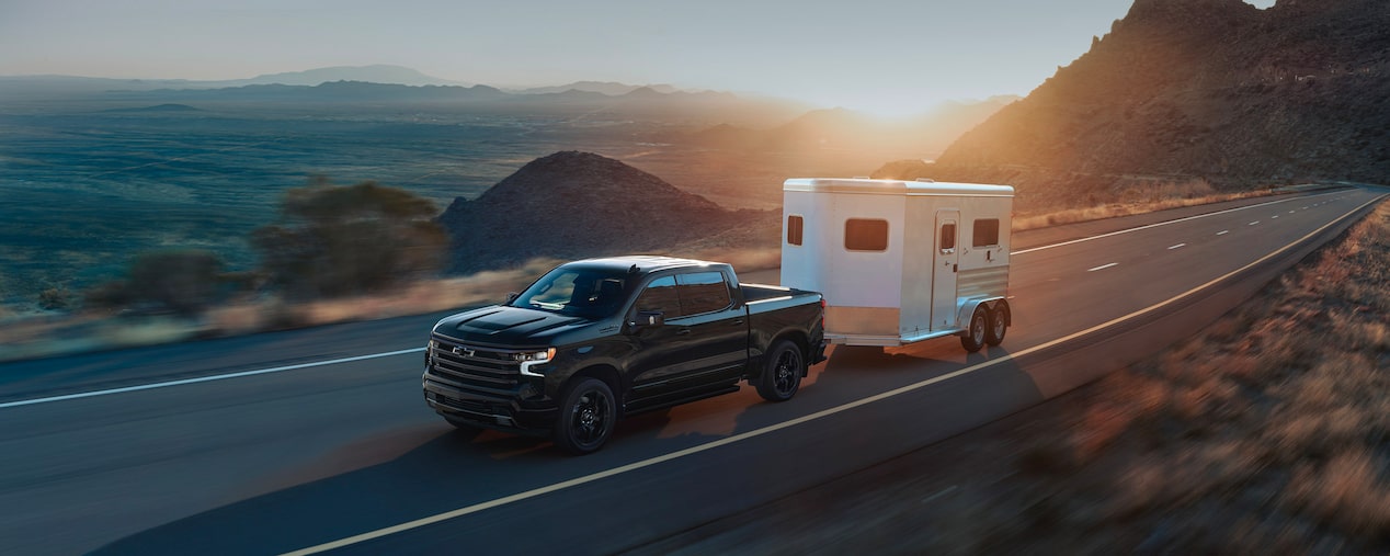 Un pick-up Chevrolet qui tire une petite remorque sur la route.