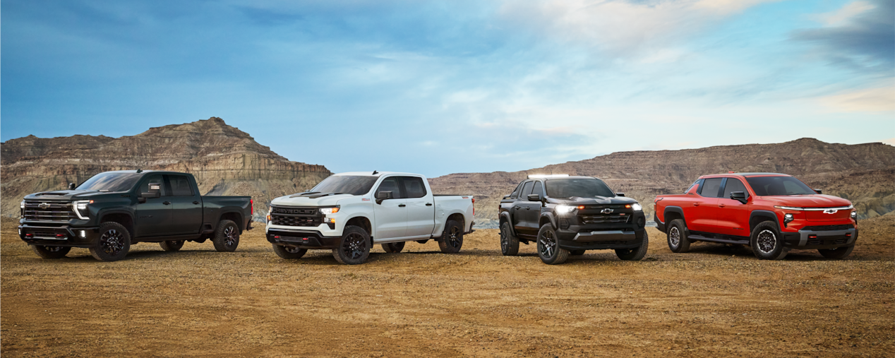 Alignement de camions Chevrolet Trail Boss stationnés dans un environnement poussiéreux.