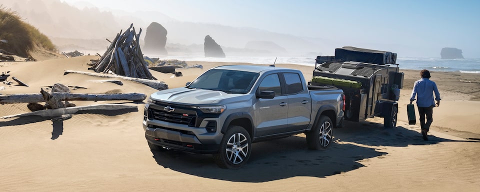 A Man Prepares to Load His Trailer with Gear as his 2023 Chevrolet Colorado Sits Parked in the Desert.