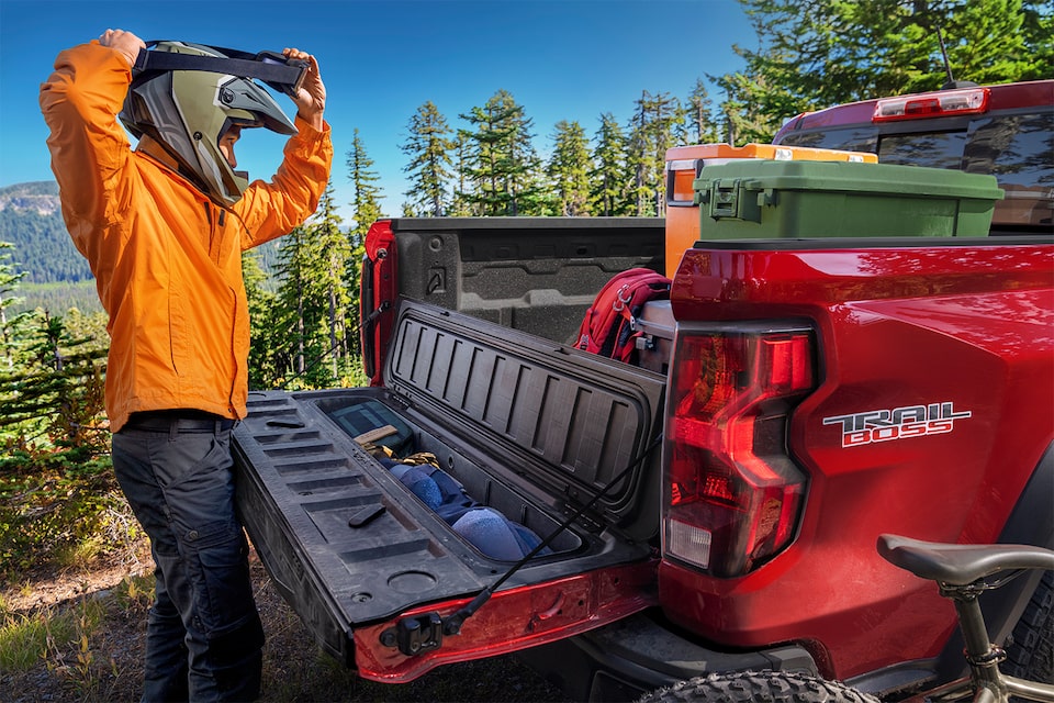 A Man Unloads Gear from His 2023 Colorado's Stow Gate.