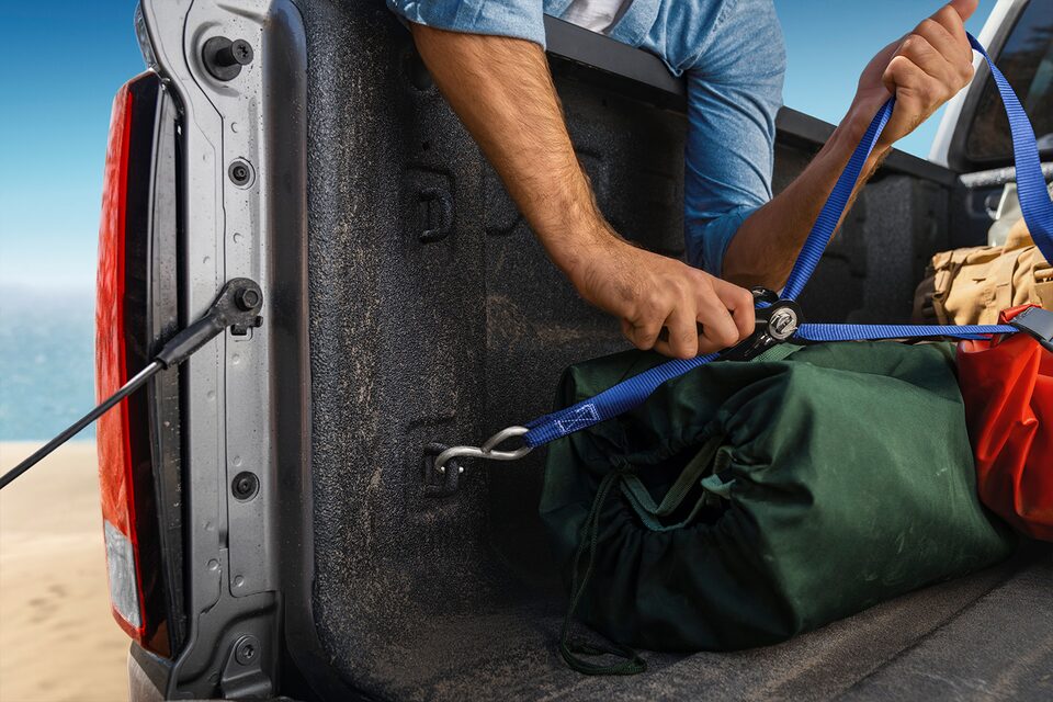 A Man Secures his Load with Straps in His 2023 Colorado Truck Bed.