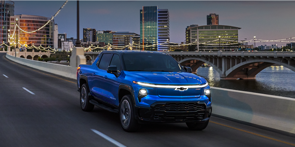 2024 Chevrolet Silverado EV driving during dusk on a city bridge.