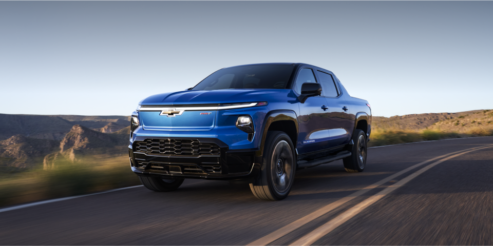 The 2024 Chevrolet Silverado EV cruising along a scenic road with mountains.