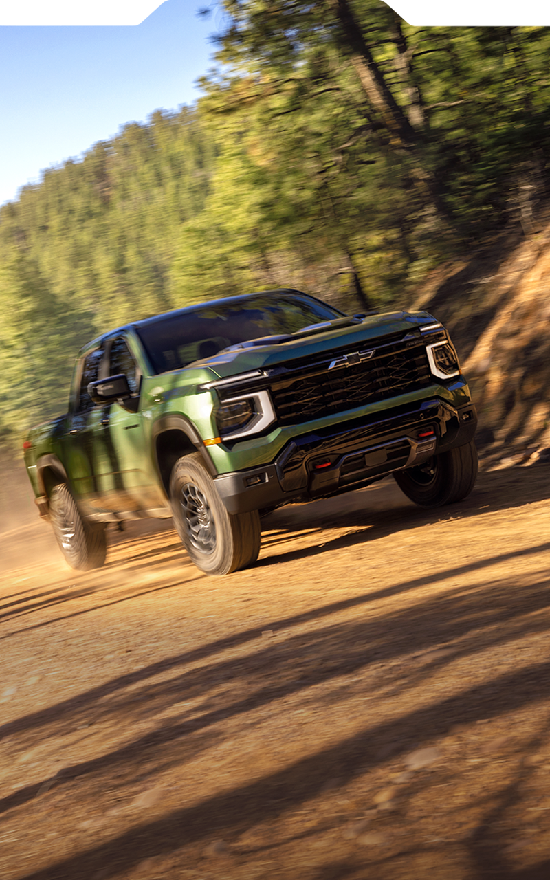 Green 2027 Chevrolet Silverado 1500 Trail Boss driving on a rugged dirt road