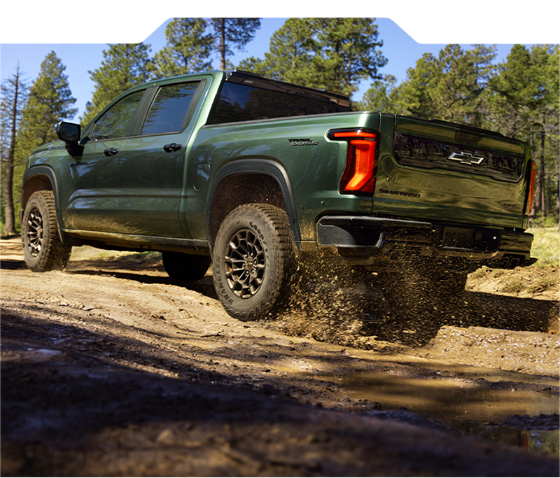 Green 2027 Chevrolet Silverado 1500 Trail Boss driving over a rugged off-road trail