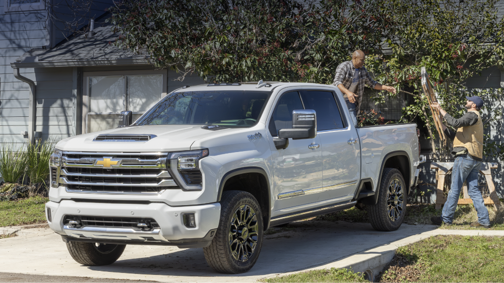 Le nouveau camionnette Chevrolet Silverado HD High Country 2027 est stationné sur une surface de gravier près d’une grange ou d’un bâtiment agricole.