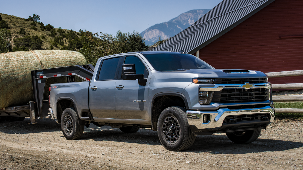 Le nouveau pick-up Chevrolet Silverado HD LT 2027 remorquant une remorque à bétail sur une ferme.