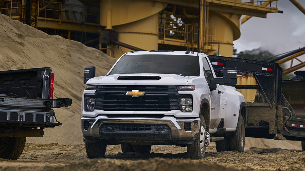 La nouvelle camionnette Chevrolet Silverado HD WT 2027 est stationnée sur un chantier industriel, avec des tas de sable et de l’équipement lourd en arrière-plan.
