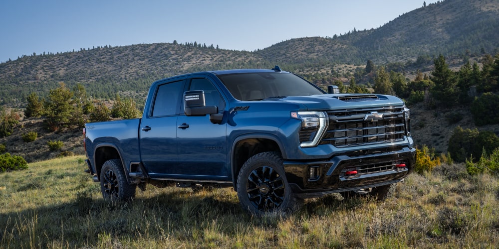 Le nouveau camion tout-terrain Chevrolet Silverado HD 2027 stationné dans un champ gazonné, vu d’un angle avant aux trois quarts.
