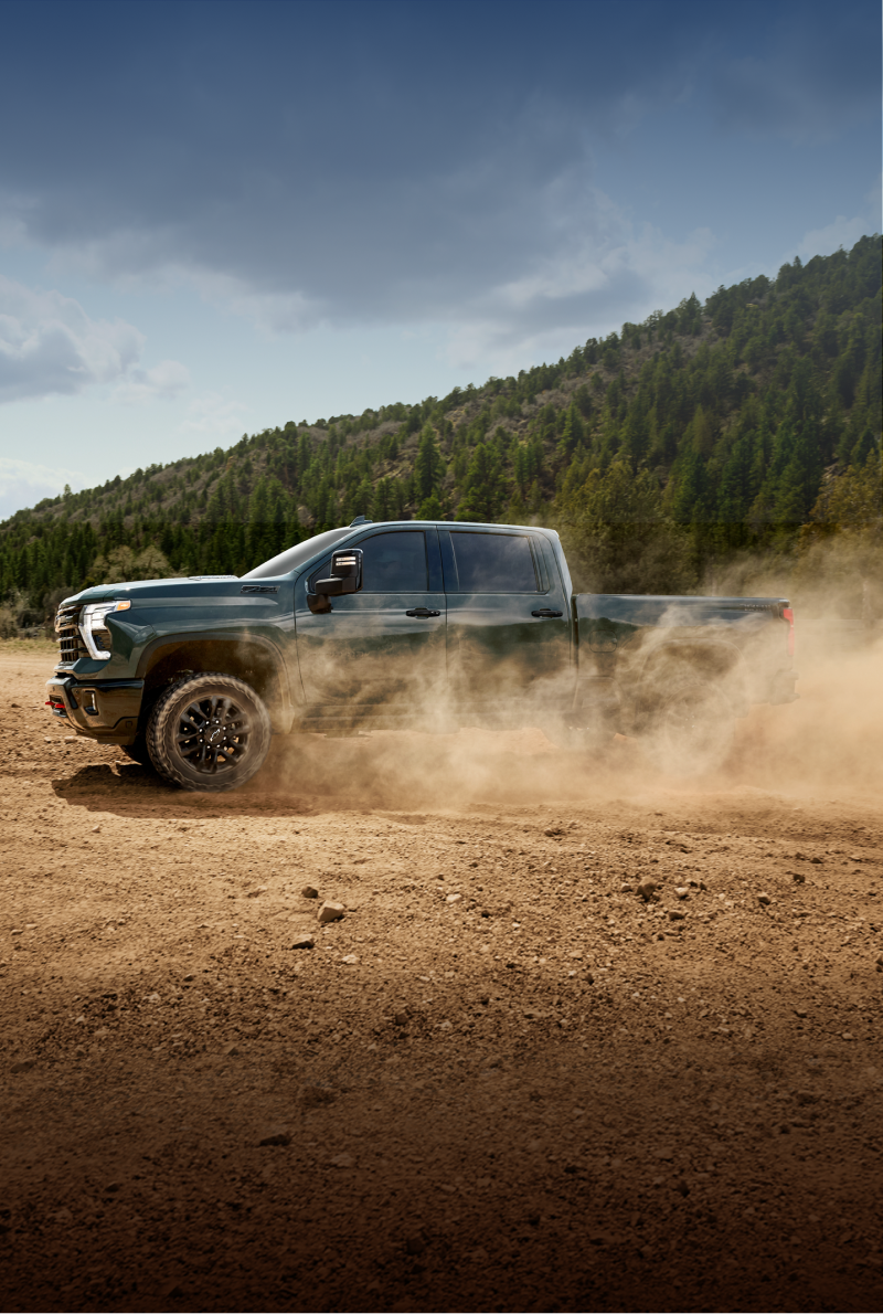 Vue avant trois quarts du nouveau camion Chevrolet Silverado HD 2027 stationné sur un sentier désertique sablonneux.