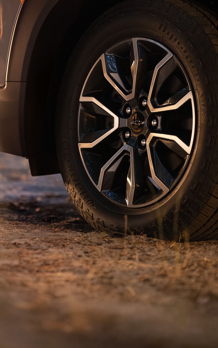 Close-up of a 2027 Chevrolet Trailblazer alloy wheel and tire on a dirt surface.