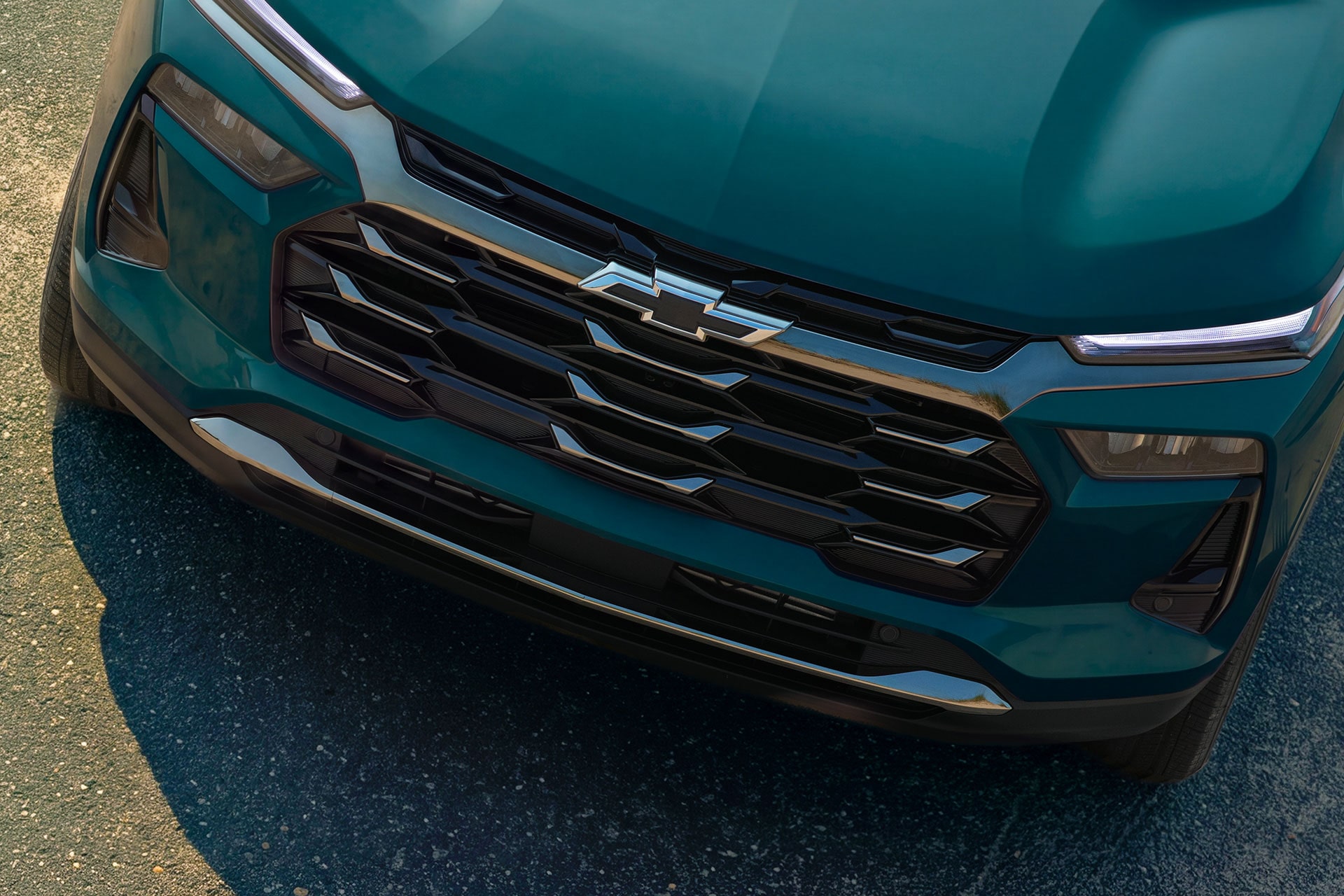 2027 Chevrolet Trax small SUV front grille and Chevrolet bowtie emblem with modern lighting elements and teal exterior finish.