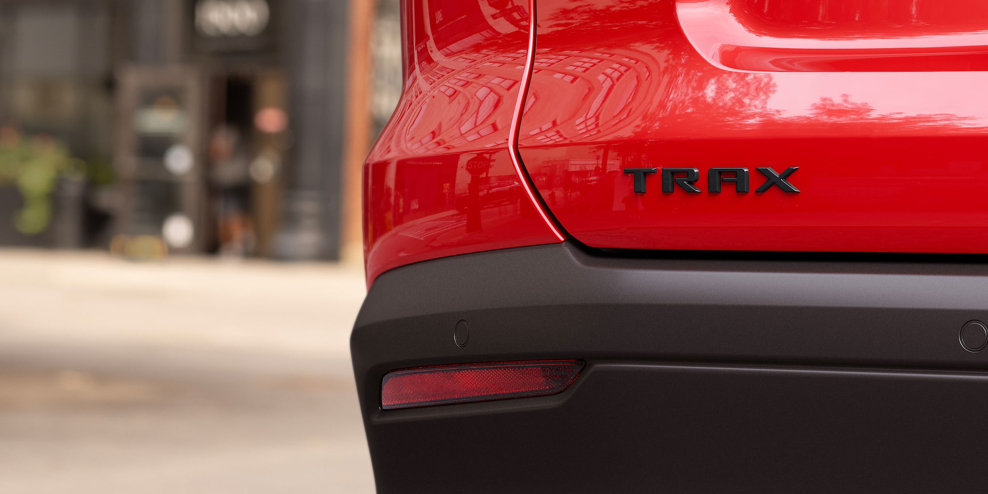 Close-up of the rear Trax badge on a red 2027 Chevrolet Trax small SUV, highlighting the vehicle’s model branding and exterior design details.