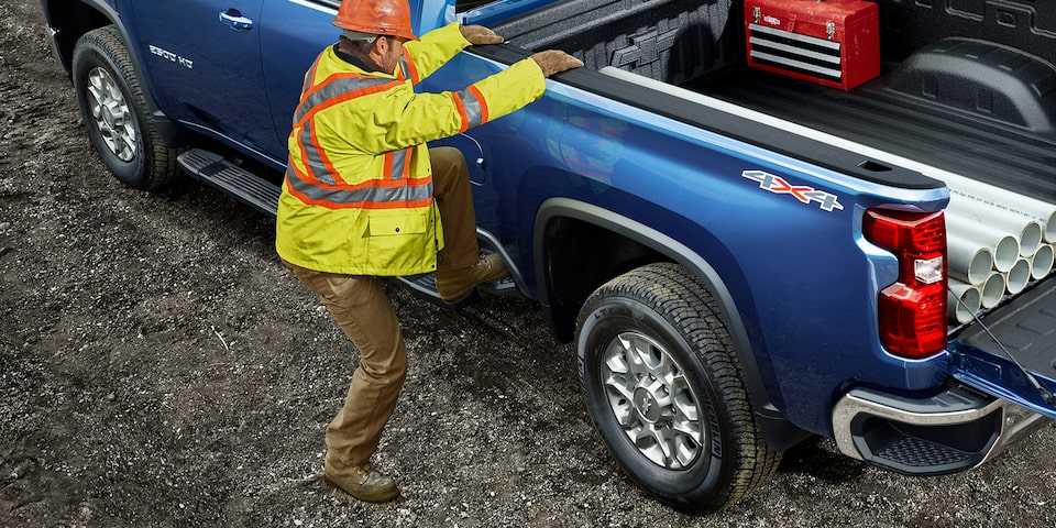 Deux hommes utilisant la benne du camion Chevrolet Silverado HD 2021 pour le travail commercial.