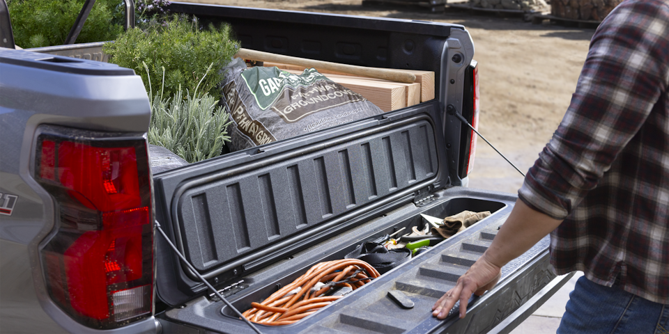 Lowered tailgate of the 2024 Chevrolet Colorado work truck revealing some stowed gardening equipment.