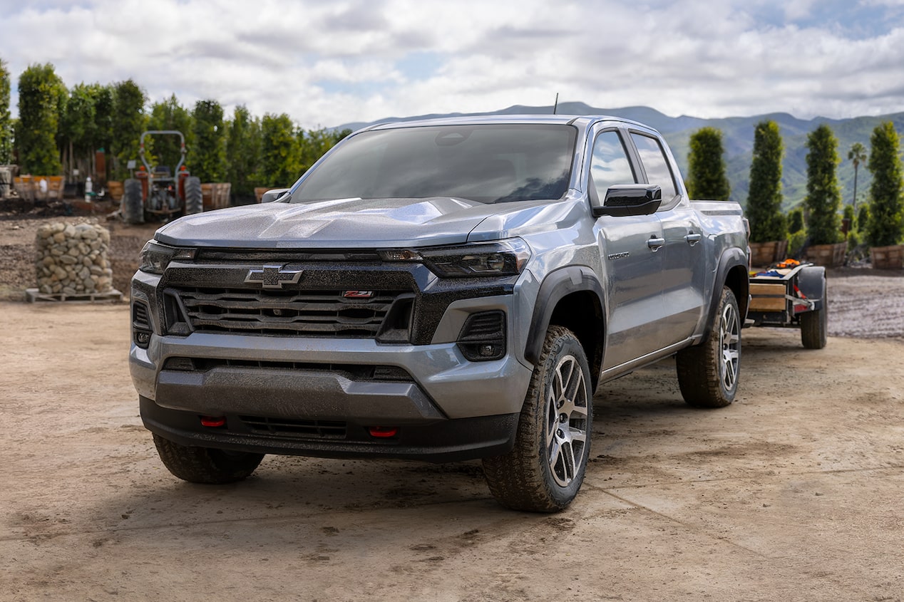 Front-side view of the 2024 Chevrolet Colorado work truck parked on a tree-lined mountaintop.