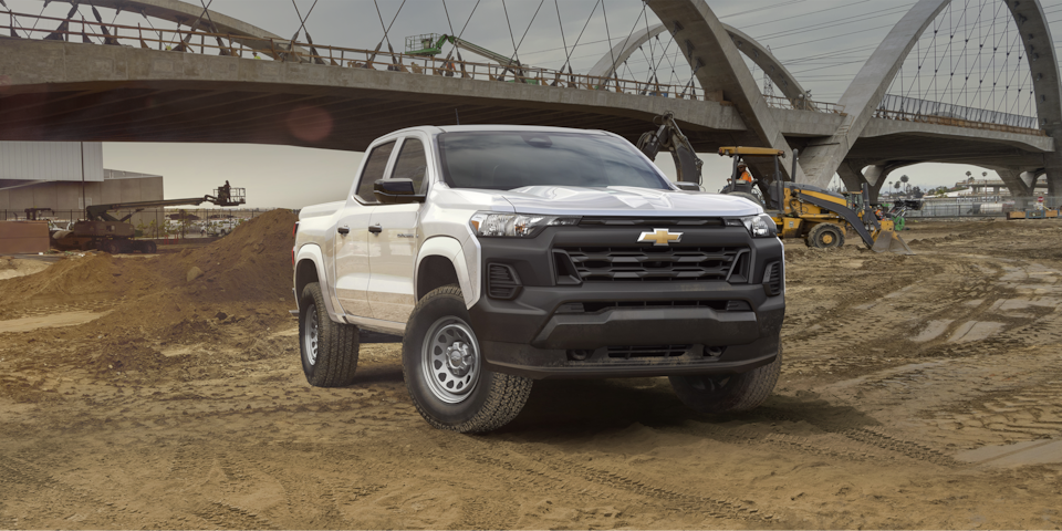 2024 Chevrolet Colorado work truck parked at a sandy construction site under a bridge.