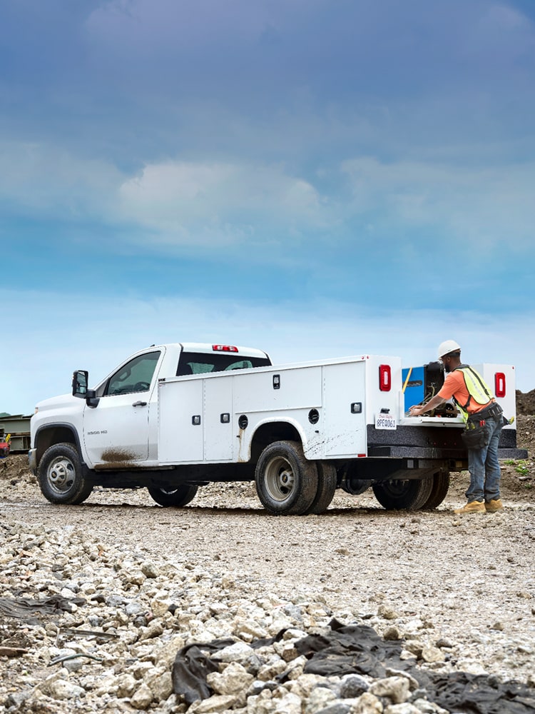 A person is putting plants in the bed of the 2026 Chevrolet Colorado work truck.