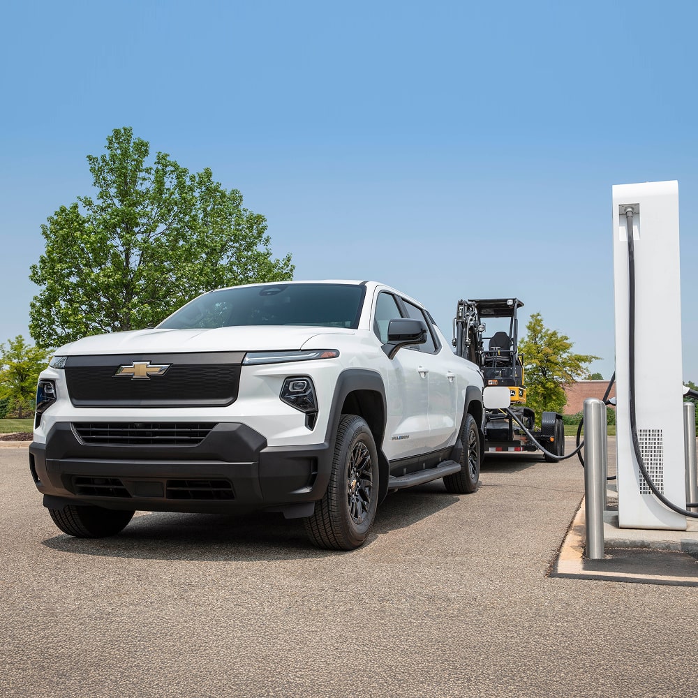 2026 Chevrolet Silverado EV Work Truck Towing Construction Equipment While Parked at a Charging Station.
