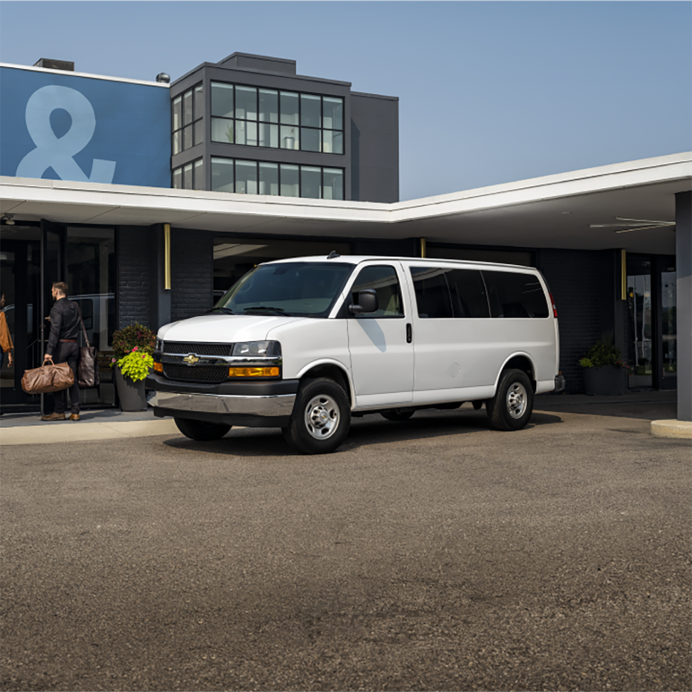 Une fourgonnette de tourisme Chevrolet Express 2026 dépose une famille à un hôtel.