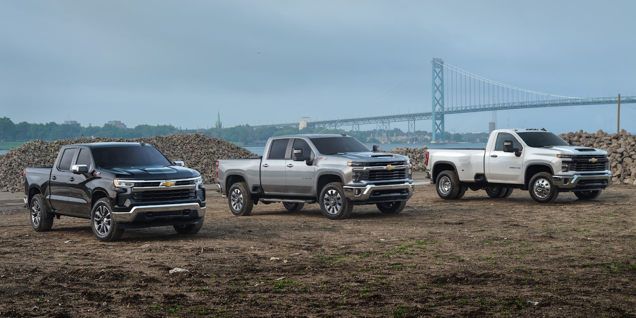 Three Chevrolet commercial trucks parked at a construction site.