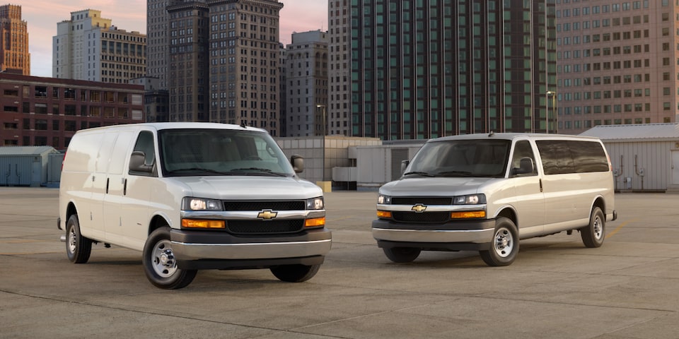 Two Chevrolet commercial Vans parked on a commercial rooftop.