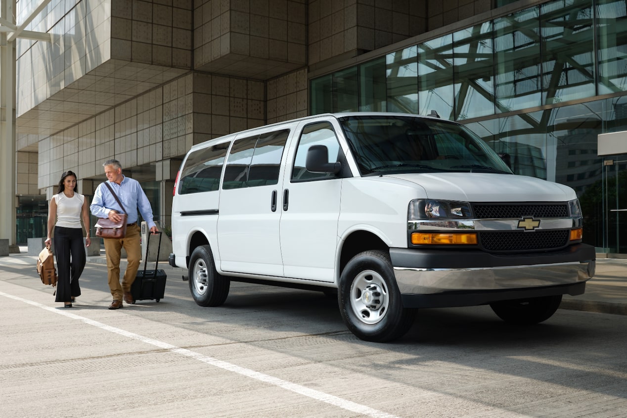 A Chevrolet Express Passenger Van parked outside an airport building.