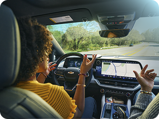 Vue arrière d’une femme parlant à un passager tout en utilisant la conduite mains libres Super Cruise dans un véhicule Chevrolet