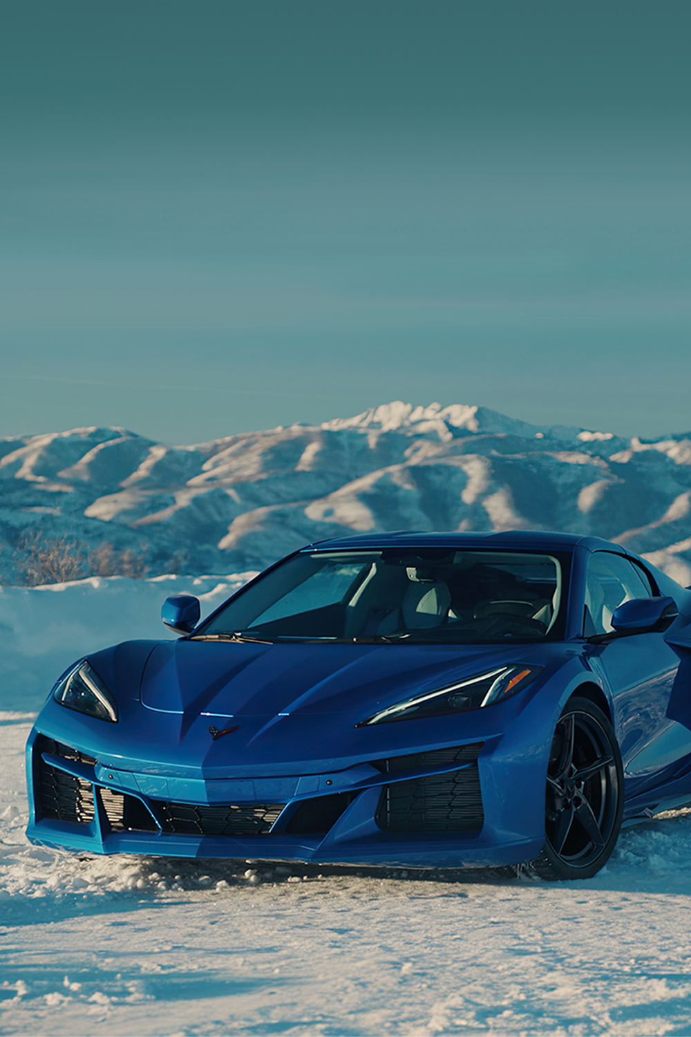 View of a 2025 Blue Chevrolet Corvette E-Ray in an Icy Plain Surrounded by Icy Mountains.