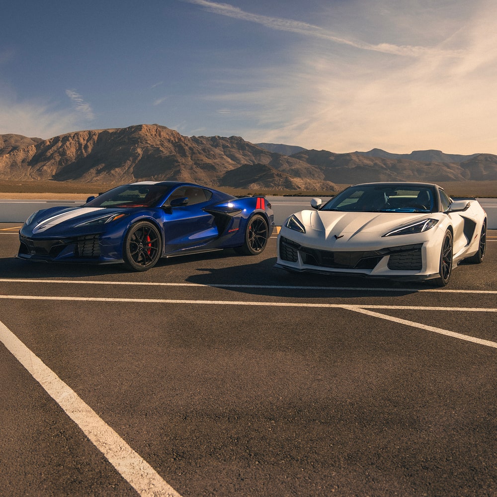 Deux Chevrolet Corvette Grand Sport 2027 sont stationnées côte à côte sur une piste de course avec des crêtes montagneuses au loin.