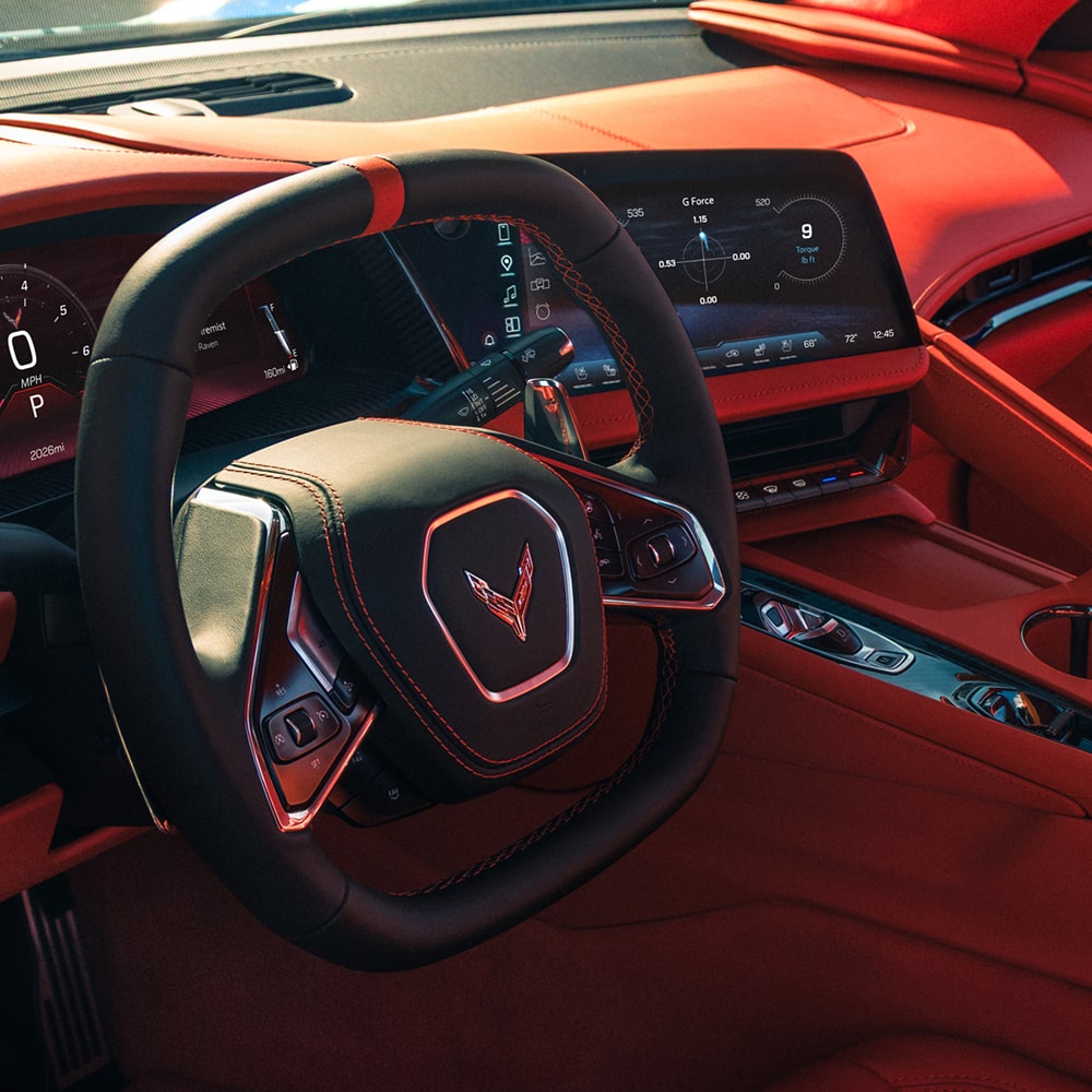L’intérieur rouge d’une Chevrolet Corvette Grand Sport 2027 présente un cockpit axé sur le conducteur avec un volant à pied plat, un tableau de bord numérique et un tableau de bord angulaire.
