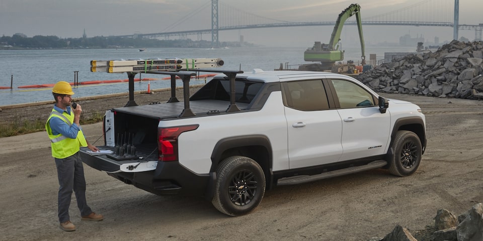 Vue latérale arrière du camion de travail Chevrolet Silverado EV 2025 avec une personne en train d’ouvrir son coffre.