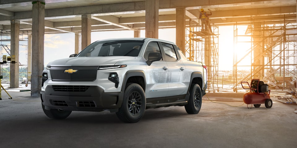 Vue latérale avant du camion de travail Chevrolet Silverado EV 2025 stationné devant un chantier.
