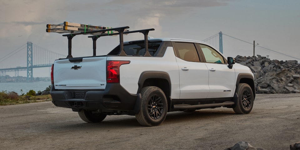 Vue latérale arrière du camion de travail Chevrolet Silverado EV 2025 en mouvement sur la route le soir.